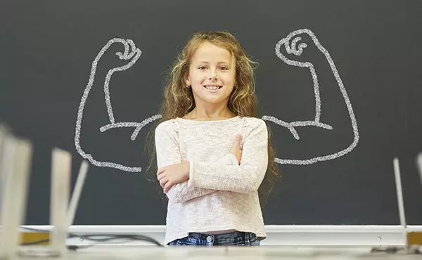 Mädchen In Schule Steht Vor Tafel Mit Muskeln